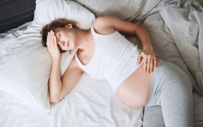 Exhausted pregnant woman suffering from insomnia or pain lying in bed.