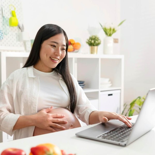 Pregnant woman using laptop at home.